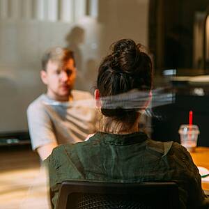 Person auf einem Stuhl sitzt Mann gegenüber Person auf einem Stuhl sitzt Mann gegenüber